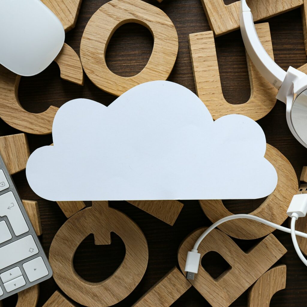White, paper cloud with gadgets on the background of wooden letters, cloud computing concept